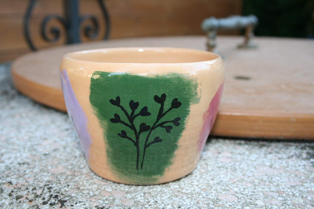 Vaso da fiori in argilla rossa con disegni floreali.