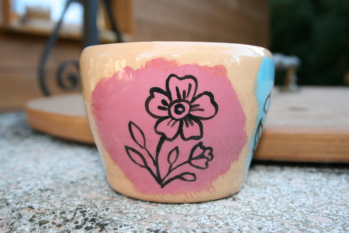 Vaso da fiori in argilla rossa con disegni floreali.