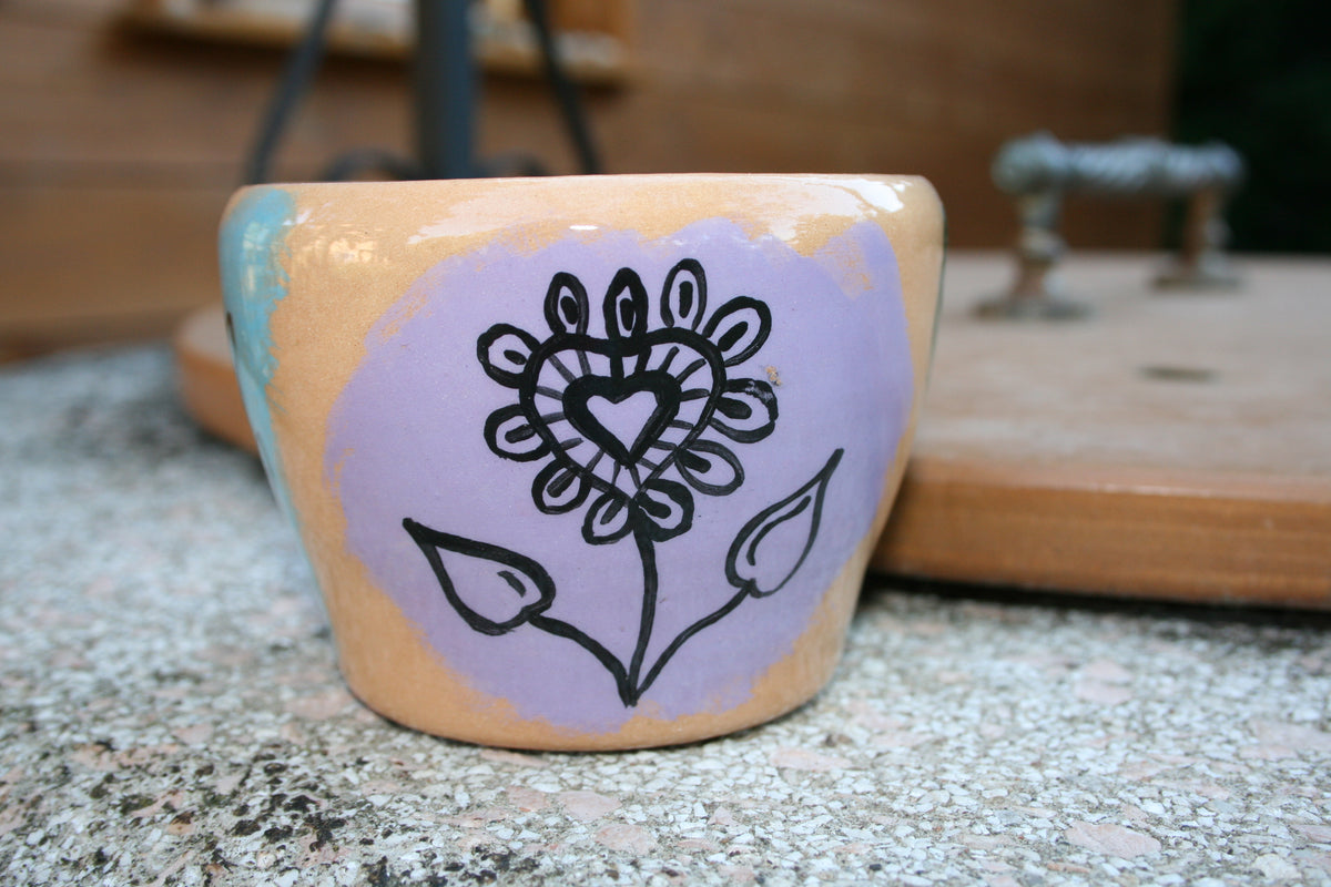 Vaso da fiori in argilla rossa con disegni floreali.
